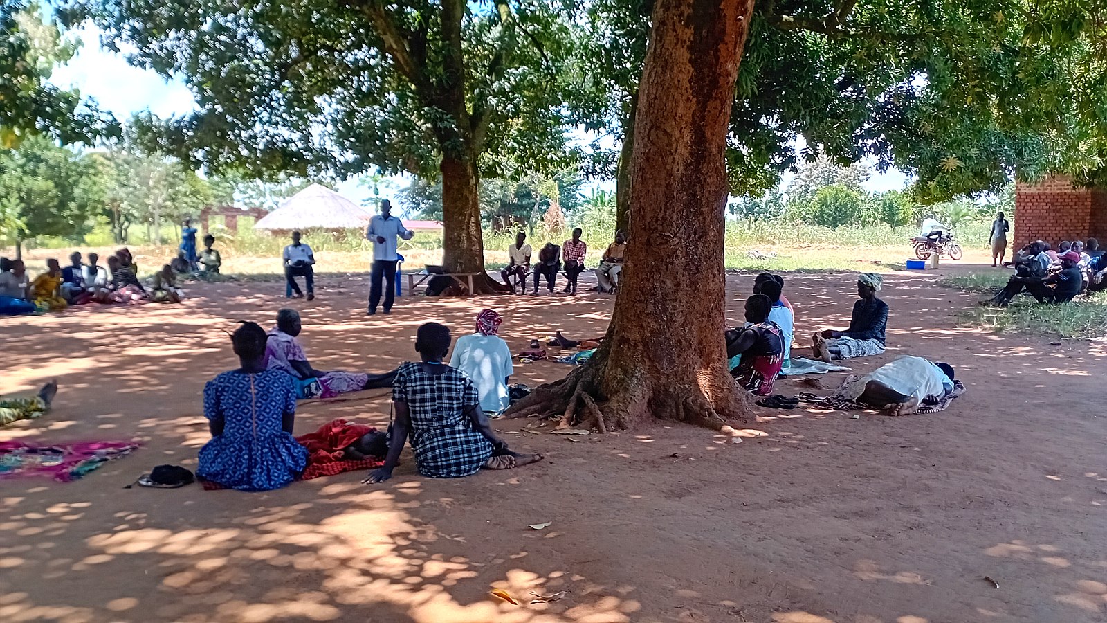 Participants seated in small groups under the trees during the dialogue in Atiak